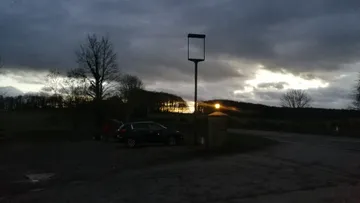 A concrete boat shape sunk in mud, overgrown with grass
