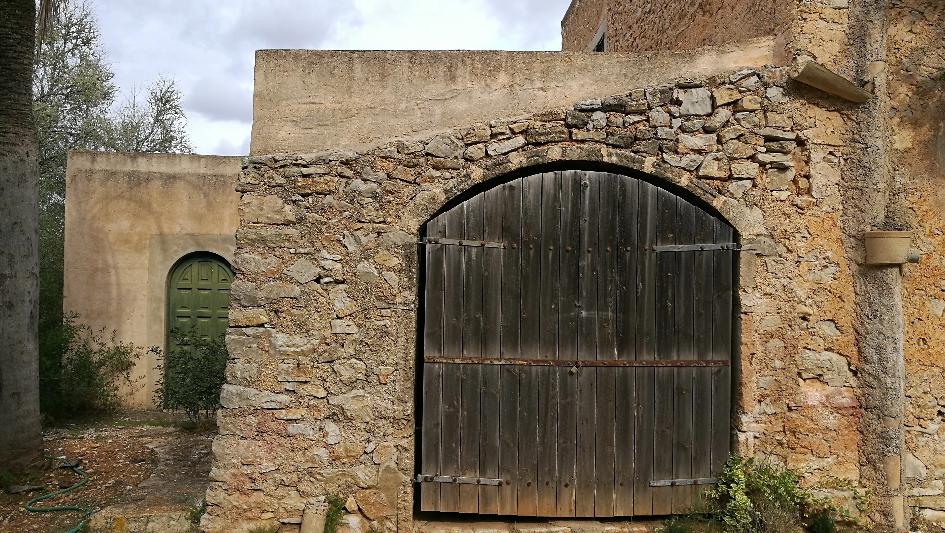 A stone building with a large wooden door, a small wooden door and a small window